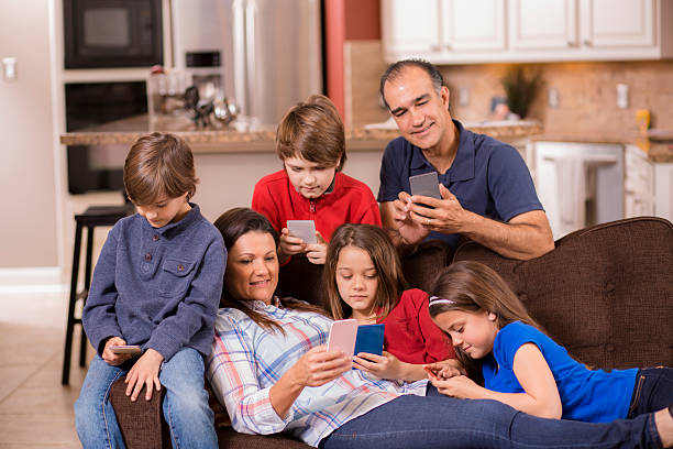 семьи с помощью мобильного телефона в домашних условиях. дети, родители). технологии. - two parent family technology mobility men стоковые фото и изображения