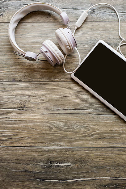 Directly above view of a old wooden table, headphones and tablet pc on it