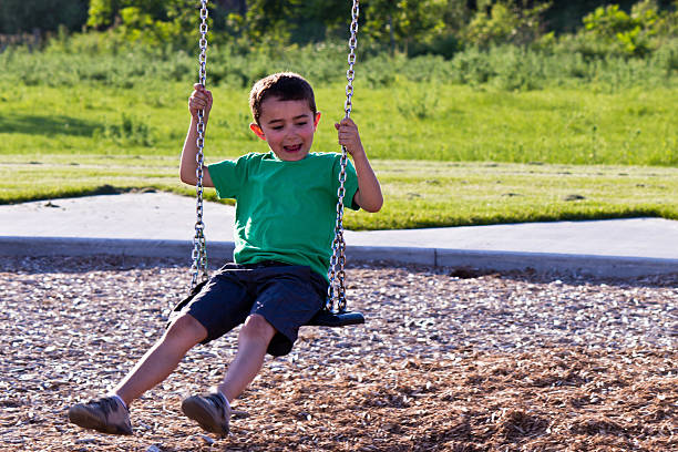 istock Happy boy on a swing at the playground 516251497