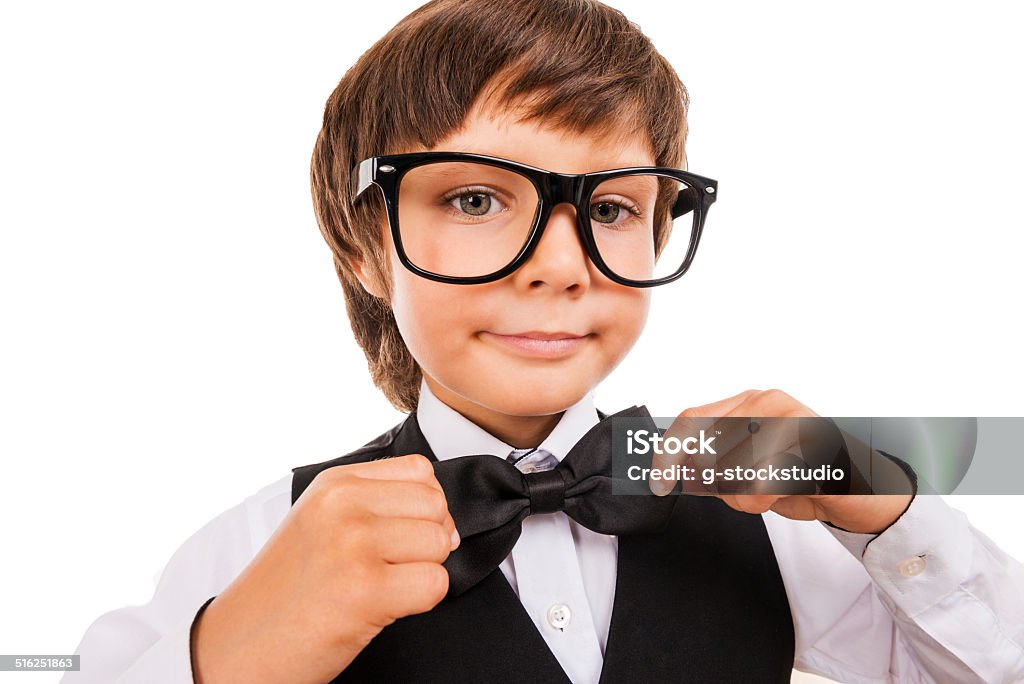 Confident in his skills Cute little boy adjusting his bow tie and looking at camera while standing isolated on white Bow Tie Stock Photo