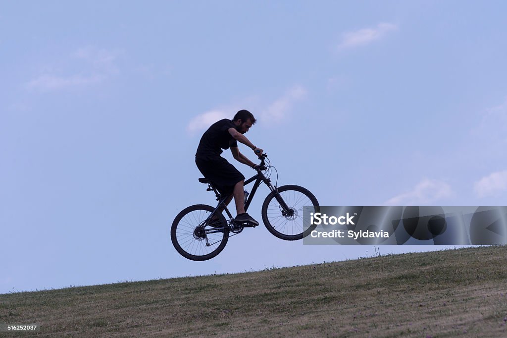 Bicycle. Young man jumping with a bike in a meadow at sunset Bicycle Stock Photo