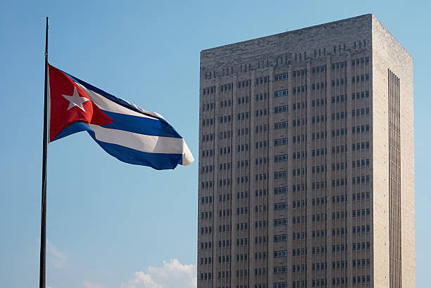 Cuban flag and the Hermanos Ameijeiras hospital at the Malecón waterfront in La Havana, Cuba