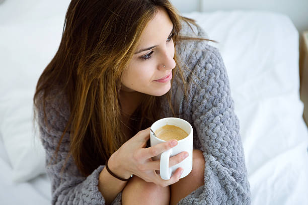 istock Beautiful young woman drinking coffee on bed. 516252530