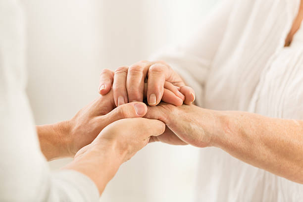 senior e giovani donne tenendo le mani - consoling close up senior adult grandparent foto e immagini stock