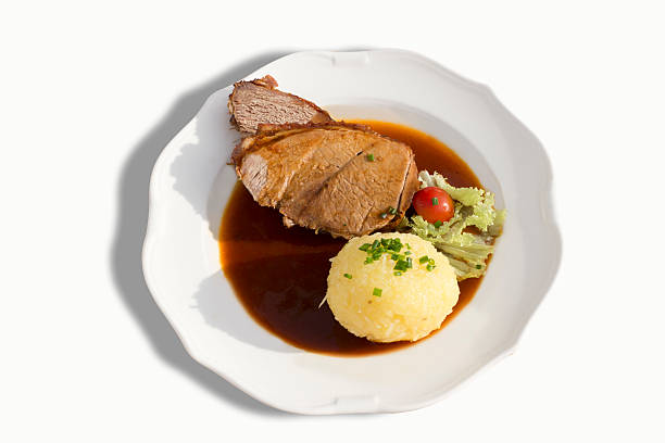 Roasted pork with dumpling and gravy served on plate