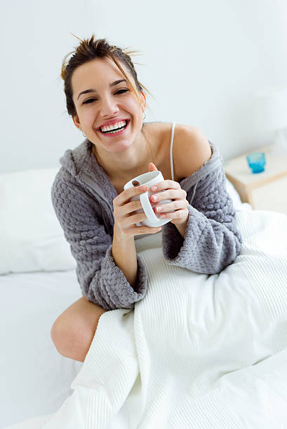 istock Beautiful young woman drinking coffee on bed. 516253324