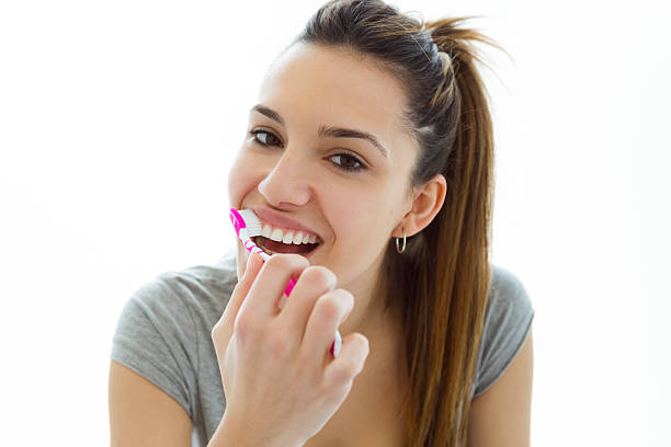 istock Pretty young woman brushing her teeth. Isolated on white. 516255250