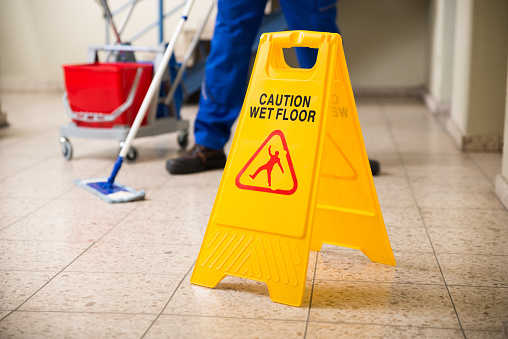 Trabajador trapeado piso con signo precaución de suelo mojado photo