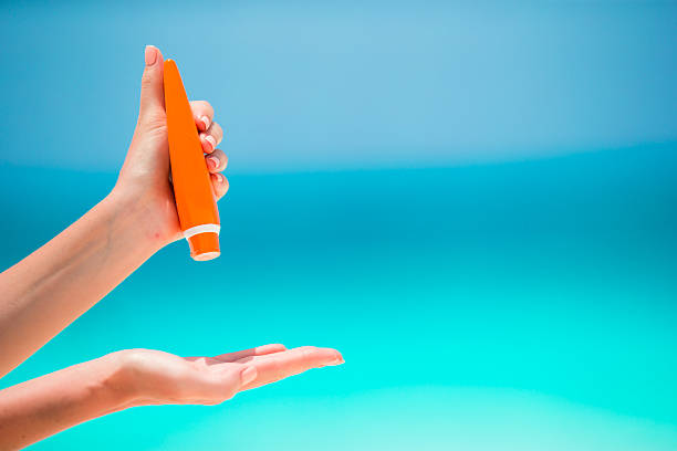 istock Female hands with suncream bottle background blue sea 516257194