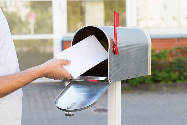 person setzen buchstaben im briefkasten - postangestellter stock-fotos und bilder