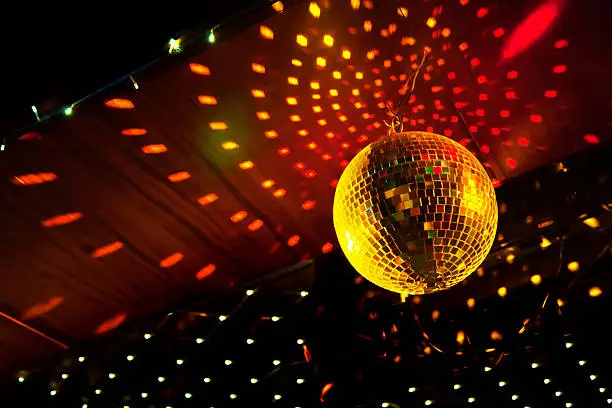 Mirror disco ball with light reflection on the ceiling, on a black background