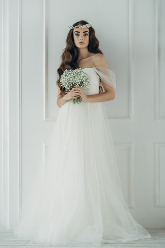 Studio shot of young beautiful bride on light background. Professional make-up and hairstyle.