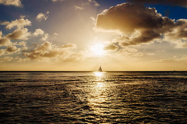 Silhouette of a boat sailing on horizon and of plane taking off at sunset with bright sun and twilight skies