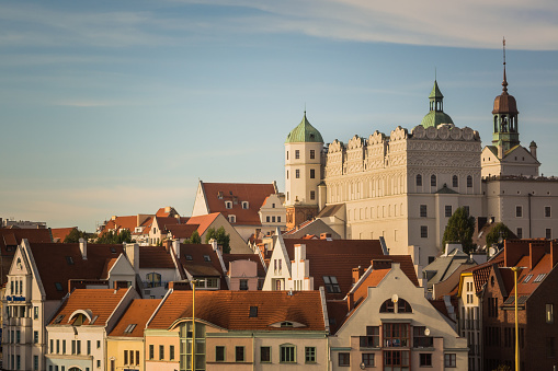 White castle with towers and green roofs and red roofs of residential and office houses in Szczecin, Poland.