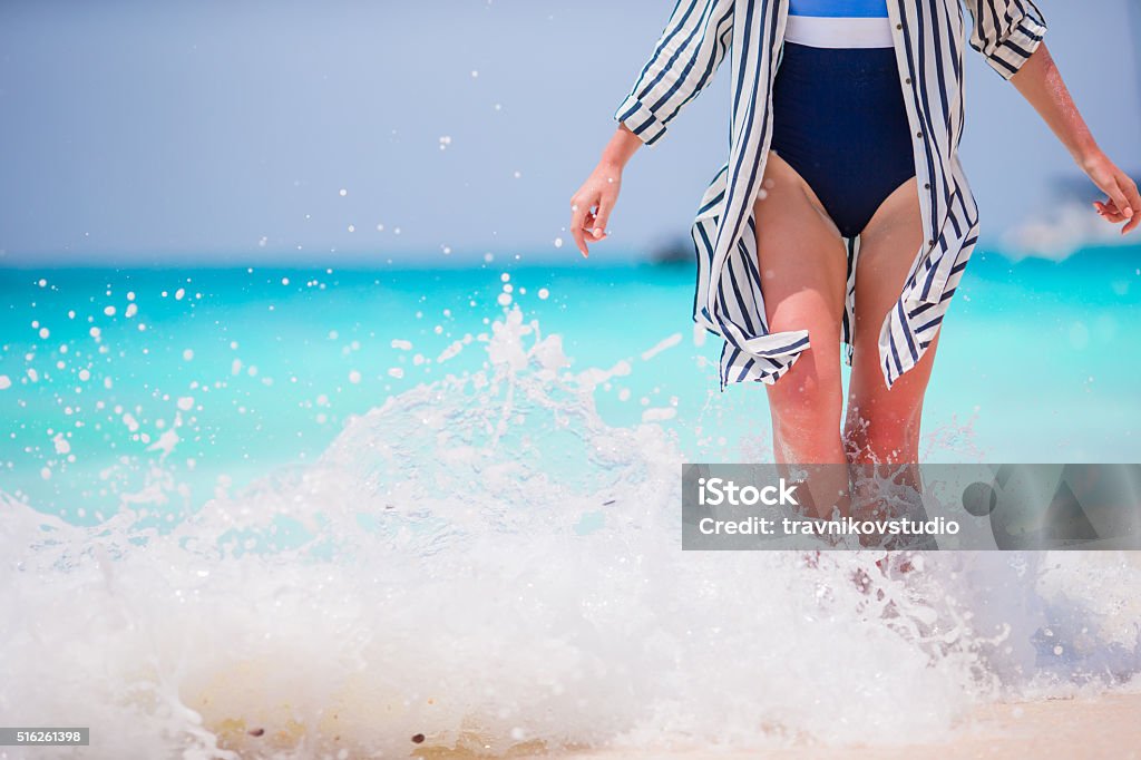 Woman's feet on the white sand beach in shallow water Close up of female feet on white sand beach Adult Stock Photo