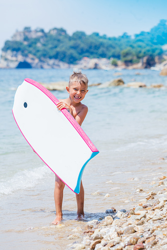 Little cute boy with surf board on the beach
