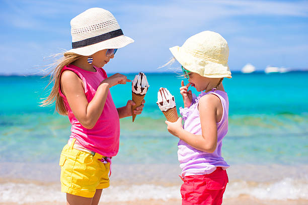 Little adorable girls eating ice cream on tropical beach Little adorable girls eating ice cream on tropical beach sand river stock pictures, royalty-free photos & images