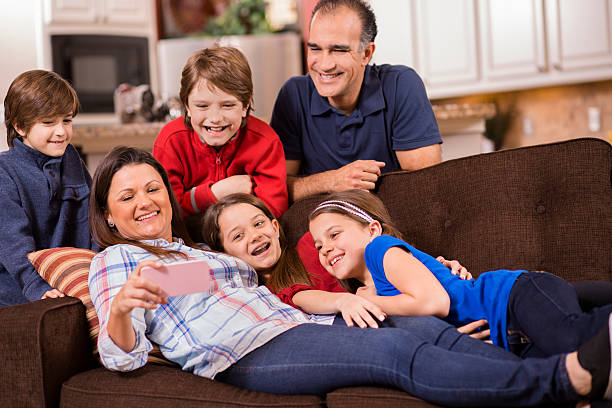 famiglia utilizzando un telefono cellulare a casa. bambini, genitori. tecnologia. - two parent family technology mobility men foto e immagini stock