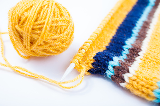 Knittes canvas, knittinf needle and yellow yarn ball