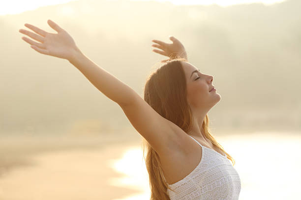 Relaxed woman breathing fresh air raising arms at sunrise Relaxed woman breathing fresh air raising arms at sunrise with a warmth golden background arms outstretched photos stock pictures, royalty-free photos & images