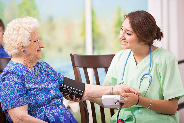 Home healthcare nurse checks blood pressure of elderly woman. Latin descent female nurse or doctor checks blood pressure of a senior woman patient.  Home or clinic setting.  Woman is over 100 years old!   over 100 photos stock pictures, royalty-free photos & images