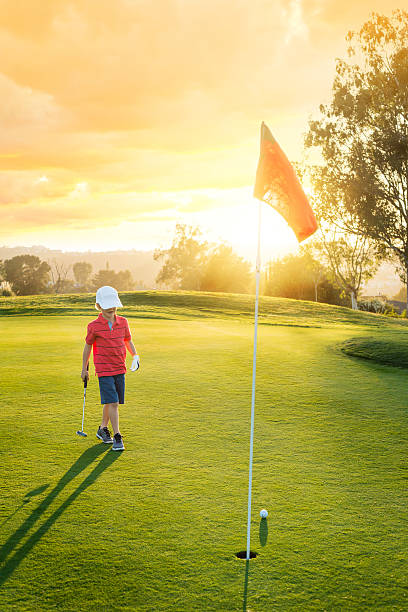 jeune garçon golfeur mise au coucher du soleil - sports flag golf individual sports sports and fitness photos et images de collection