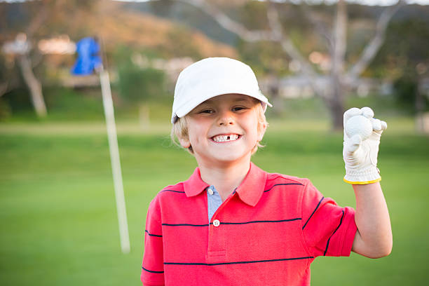 молодой мальчик играет в гольф. на тренировочную площадку вокруг лунки - child swing swinging balance стоковые фото и изображения