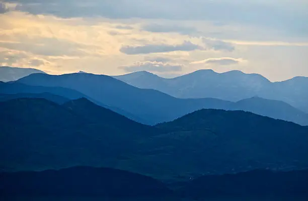 The ridges of the Rocky Mountains are layers of blue silhouettes when backlit by the evening sun