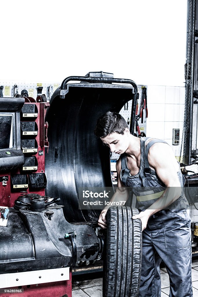 Wheel Balancing Young man put tyre on machine for balancing tyre. Craftsperson Stock Photo