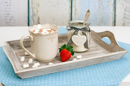 Cup of hot cocoa with marshmallows and strawberry on a table