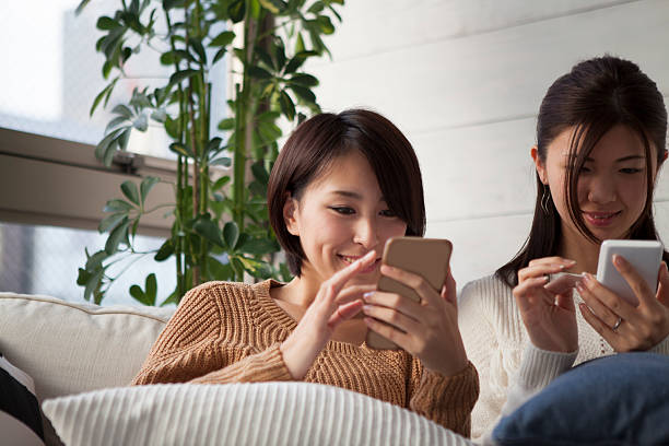 mujer mirando en el teléfono inteligente en el sofá - sofa music teenager friendship fotografías e imágenes de stock