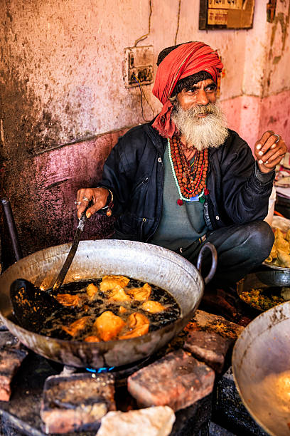 Indian street vendor preparing food, Jaipur, India Old Indian man preparing food on the street, Jaipur - The Pink City, Rajasthan, India. Jaipur is known as the Pink City, because of the color of the stone exclusively used for the construction of all the structures. india indian culture market clothing stock pictures, royalty-free photos & images