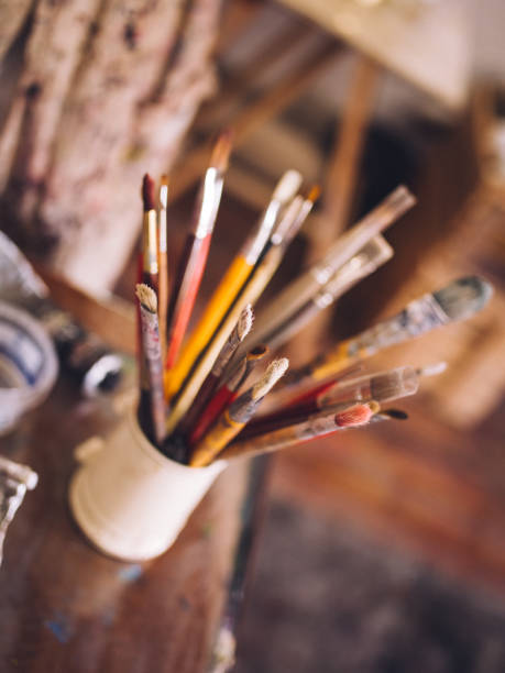 istock Collection of dirty old artist's paintbrushes in a container 516295582