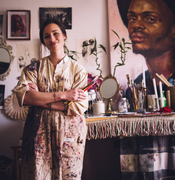 istock Artist in smock standing with paintbrushes at her work table 516296366