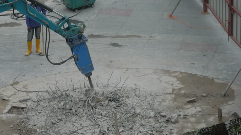 Worker drilling concrete with compressor on the street