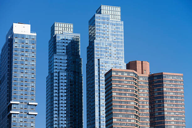 View of historic and contemporary buildings around City Hall Park in Lower Manhattan, New York City. The mix of architectural styles, from classic facades to sleek modern towers, creates a striking contrast beneath a dramatic cloudy sky.