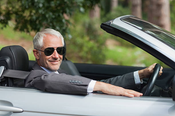 istock Smiling mature businessman driving classy cabriolet 516313447