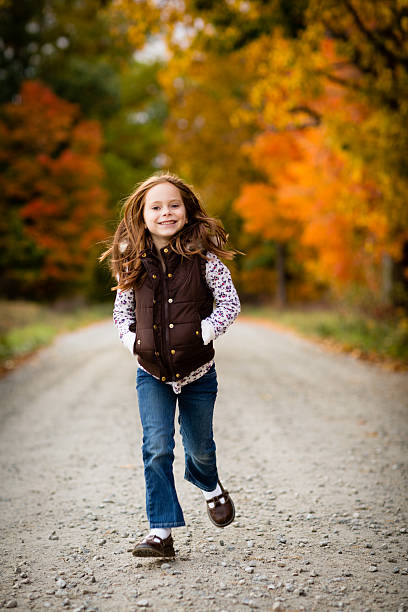 menina caminhando em direção à câmera, do lado de fora em um dia de outono - little girls autumn child red hair - fotografias e filmes do acervo