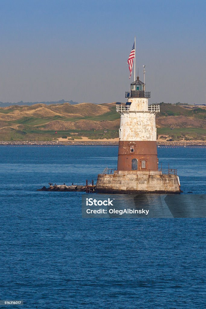 Robbins Reef Light, Bayonne, NJ. Robbins Reef Light, with Bayonne Golf Course in background, Bayonne, NJ, USA. The image lit by early morning sun. The Robbins Reef Light Station is a sparkplug lighthouse located off Constable Hook in Bayonne, along the west side of Main Channel, Upper New York Bay. The tower and integral keepers quarters were built in 1883. Lighthouse Stock Photo