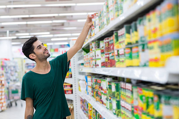 Taking canned food Young customer taking canned food from the shelf in the store canned food stock pictures, royalty-free photos & images