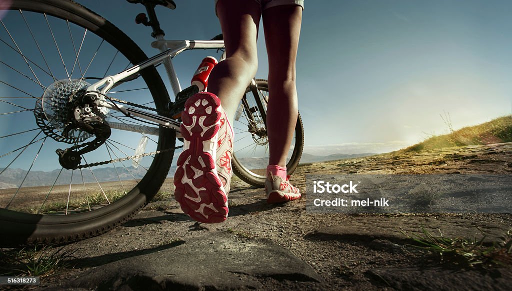 Runnning shoes on runner Athlete woman is running with her extreme mountain bike outdoors Cycling Stock Photo