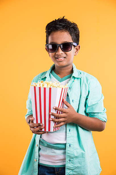 istock Joyful indian kid with big box of popcorn, eating popcorn 516321922
