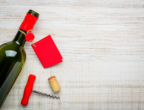 Opened wine bottle and red label with cork screw and copy space