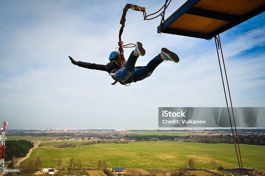 Ropejumping Ropejumping: girl jumping from a height in the equipment for mountaineering and helmet Bungee Jumping Stock Photo