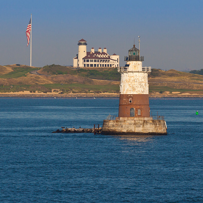 Robbins Reef Light, with Bayonne Golf Club in background, Bayonne, NJ, USA. The image lit by early morning sun. The Robbins Reef Light Station is a sparkplug lighthouse located off Constable Hook in Bayonne, along the west side of Main Channel, Upper New York Bay. The tower and integral keepers quarters were built in 1883.