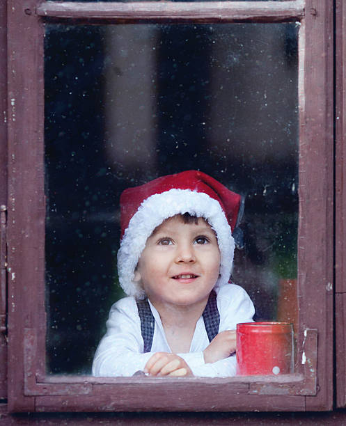 istock Adorable boy, looking through window, waiting for Santa 516334421
