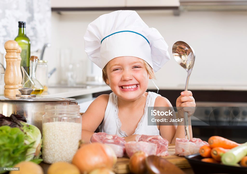 Baby girl cooking with meat Laughing baby girl cooking with meat at home kitchen 4-5 Years Stock Photo