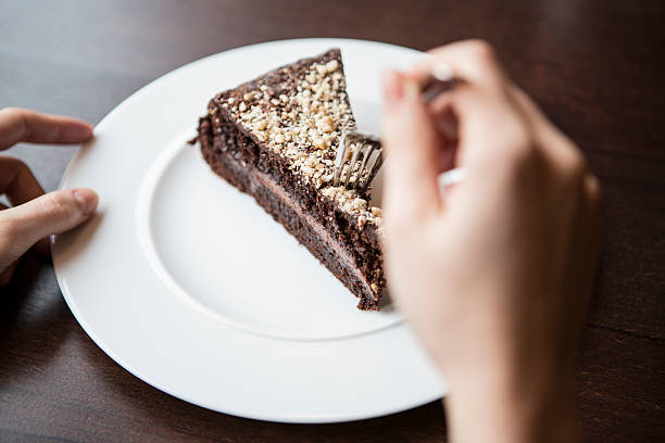 istock Close-up of woman's hand holding fork to chocolate pastry 516335583