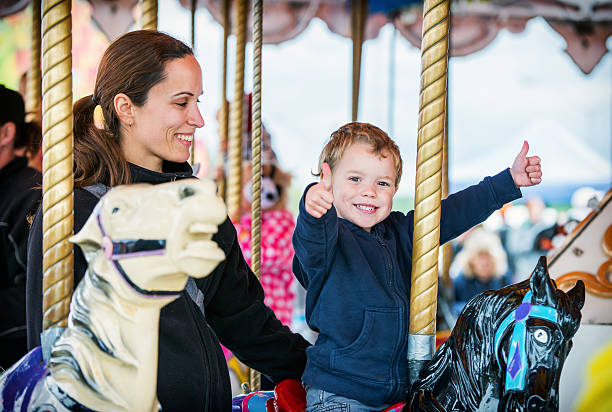 мальчик и две большие пальцы вверх с матерью на carousel - agricultural fair стоковые фото и изображения