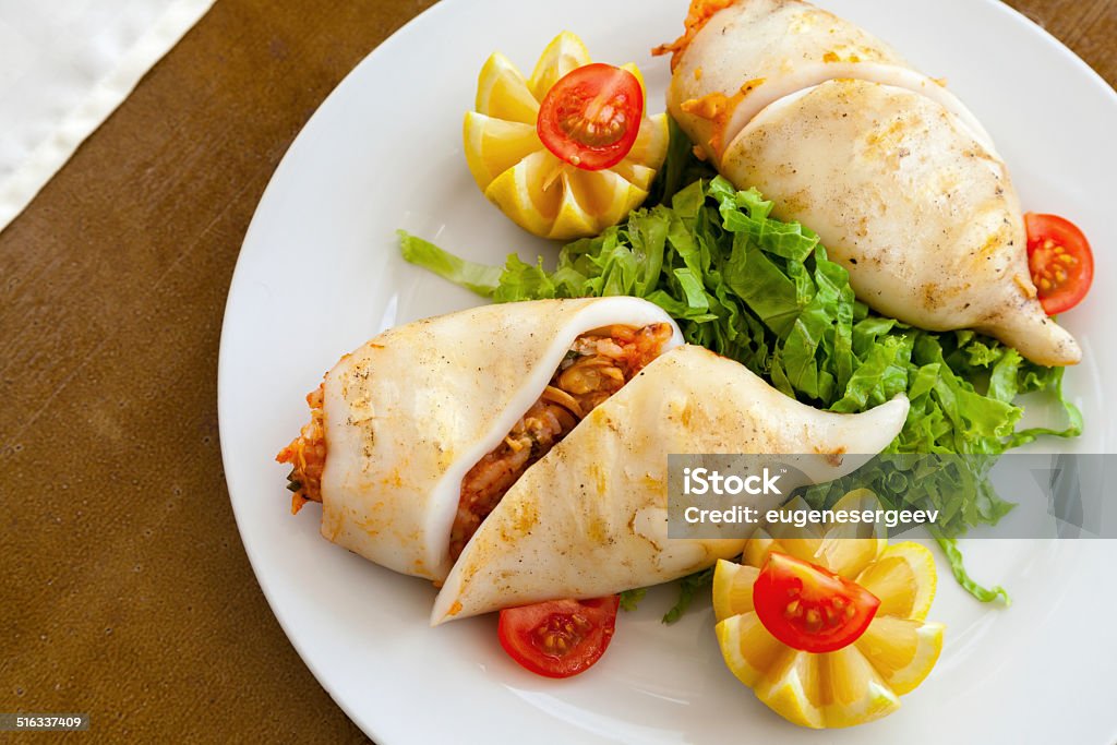 Squid stuffed with seafood in white plate on wooden table Calamari Stock Photo